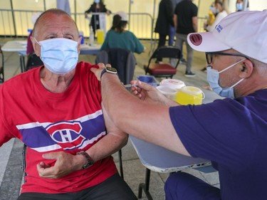 Habs fan Fernand Bechard gets vaccinated by nurse El Mahfoud Mourouane during a walk-in vaccination clinic outside the Bell Centre prior to the Canadiens playoff game against the Vegas Golden Knights in Montreal on Friday, June 18, 2021.