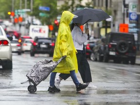 Montrealers cross Metcalfe St. in the rain in Montreal Wednesday June 30, 2021.