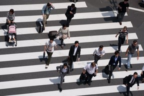 Pedestrians walk cross an intersection in Tokyo, Japan, on Tuesday, May 24, 2016. Japan's service producer price index (PPI) figures are scheduled to be released on May 26, 2016.