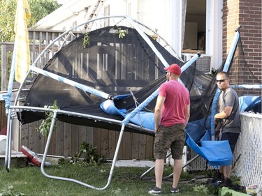 A family assesses the damage, mostly broken trees, windows and a trampoline, after a tornado struck in Mascouche north of Montreal on Monday, June 21, 2021.