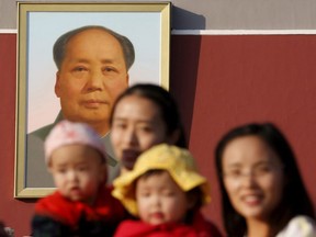 Two women and their babies pose for photographs in front of the giant portrait of late Chinese chairman Mao Zedong on the Tiananmen Gate in Beijing on Nov. 2, 2015.