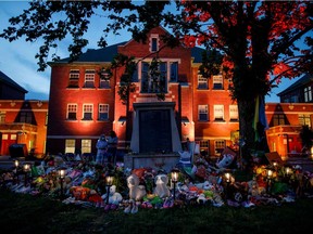 A makeshift memorial to honour the 215 children whose graves have been discovered buried near the facility is seen as orange light drapes the facade of the former Kamloops Indian Residential School in Kamloops, British Columbia, Canada, on June 2, 2021.