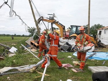 Hydro crews pull down damaged lines in the aftermath of a tornado that touched down on the previous day in Mascouche on June 22, 2021.