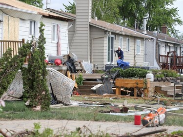 Michel Vachon clears debris from his deck in the aftermath of a tornado that touched down on the previous day and claimed the life of his neighbour, in Mascouche on June 22, 2021.