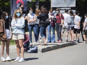 People wait in line to receive a COVID-19 vaccine shot at the Bill-Durnan Arena in Montreal on Monday, May 24, 2021.