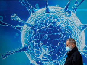 FILE PHOTO: A man wearing a protective face mask walks past an illustration of a virus outside a regional science centre amid the coronavirus disease (COVID-19) outbreak, in Oldham, Britain August 3, 2020. REUTERS/Phil Noble/File Photo