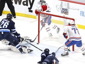 Canadiens centre Nick Suzuki (14) scores a goal against Winnipeg Jets goaltender Connor Hellebuyck (37) in the first period in Game 1 of the second round of the 2021 Stanley Cup Playoffs at Bell MTS Place in Winnipeg on June 2, 2021.