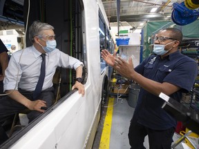 Federal Minister of Innovation, Science and Industry François-Philippe Champagne chats with a worker as he  checks out the driver's seat of a bus under construction during a tour of the Nova Bus plant on Tuesday, June 8, 2021 in St-Eustache.