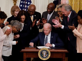 U.S. President Joe Biden is applauded as he reaches for pen to sign the Juneteenth National Independence Day Act into law as Vice President Kamala Harris stands by in the East Room of the White House in Washington, U.S., June 17, 2021.