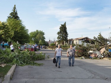 People walk past debris after a tornado touched down in Mascouche on Monday, June 21, 2021.