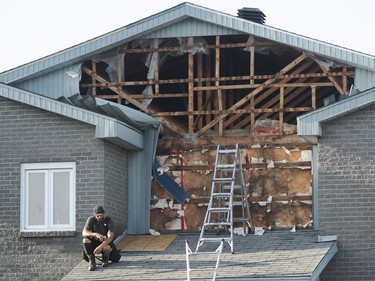 A man pauses as he repairs damage to his building after a tornado touched down in Mascouche on Monday, June 21, 2021.
