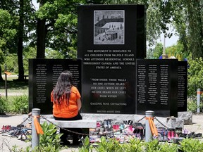A visitor sits at the Walpole Island First Nation monument dedicated to the children from the southwestern Ontario community who attended residential schools.