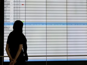 A passenger looks at the nearly empty international flight schedule board at Montreal's Trudeau airport on Monday, June 21, 2021.