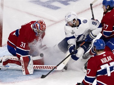 Tampa Bay Lightning centre Tyler Johnson (9) watches Montreal Canadiens goaltender Carey Price (31) shut him down as Montreal Canadiens defenceman Alexander Romanov (27) tries to clear him  in the crease during Game 4 of the Stanley Cup final in Montreal on Monday, July 5, 2021.