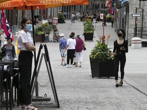 A restaurant employee stands outside looking for customers on St-Paul St. in Old Montreal on July 7, 2021.