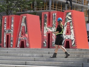 A worker walks past the newly installed display for the Just For Laughs Festival at Place des festivals on Wednesday, July 14, 2021, during the COVID-19 pandemic.