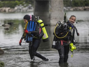 Diver Frédéric Fortin with a bottle found in the waters on Tekakwitha Island in Kahnawake on Saturday, July 17, 2021. On the left is Claudine Cantin. They were taking part in a operation by various groups, including volunteer divers, to clean up the shoreline and surrounding area.