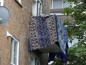 Blankets and towels drape the balcony of an apartment where a woman was found slain July 19 in Montreal's Parc-Extension district.
