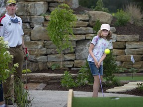 Sophie Goodfellow watches as her ball flies over a hill as her father Patrick looks on at the newly opened Miniature Golf at Golf Dorval last Friday.