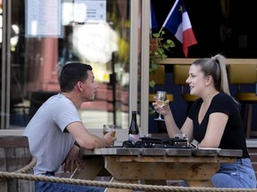 Maxime Fitzbay and Julie Belanger share a drink and an oyster plate on the sidewalk terrace of Le Fricot in Montreal on Thursday, July 22, 2021.