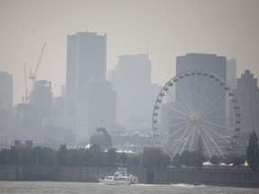 A small ferry arrives in the Old Port of Montreal as haze and smog fills the skyline as seen from Île Sainte-Hélène, on Monday, July 26, 2021. The smog, caused by forest fires in northwestern Ontario, prompted a warning from Environment Canada. The situation was expected to gradually improve on Tuesday.