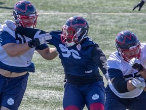 Offensive-guard Kristian Matte, left, and defensive-lineman Michael Wakefield, centre, tangle during Alouettes practice at the Olympic Stadium in Montreal on Wednesday, July 28, 2021.