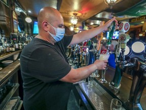 Manager Carlos Bustamante draws a pint of beer behind the bar at McKibbins Irish Pub on August 8, 2020.