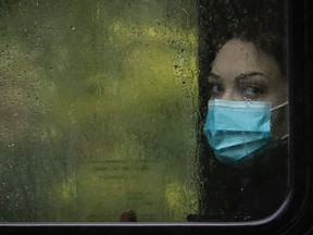 A masked bus passenger peers out into the rain in Montreal.