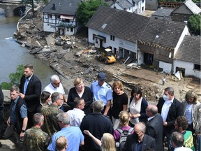 German Chancellor Angela Merkel (3rd L, 1st row) and Rhineland-Palatinate State Premier Malu Dreyer (5th L, 1st row) stand on a bridge during their visit in the flood-ravaged areas to survey the damage and meet survivors on Sunday, July 18, 2021, in Schuld, near Bad Neuenahr-Ahrweiler, Rhineland-Palatinate state, western Germany. Extreme downpours caused devastating floods this week in Germany and other parts of western Europe devastating the region. The death toll across Germany and Belgium has risen to at least 180 as rescue workers continue their efforts and communities begin to clear the debris left by the receding waters.