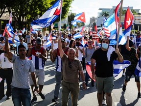 People hold Cuban and U.S. flags as they march during a protest showing support for Cubans demonstrating against their government in Miami on Friday, July 16, 2021.