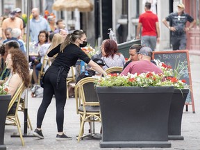 A server wears a face mask as she tends to customers in Old Montreal, Sunday, July 18 2021.