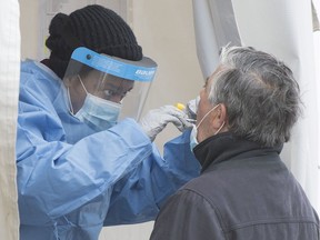 A health-care worker swabs a man at a walk-in COVID-19 test clinic in Montreal North in May 2020.