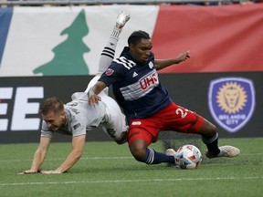 New England Revolution defender Jon Bell (23) clears the ball from the box ahead of CF Montreal midfielder Djordje Mihailovic (8) during the first half of an MLS soccer match, Sunday, July 25, 2021, in Foxborough, Mass.