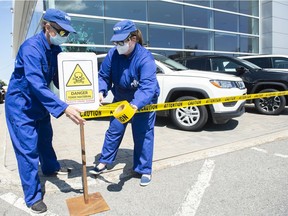 Members of a group called Ministère de la Nouvelle Normalité wrap caution tape around SUVs at a dealership to highlight the ongoing climate crisis in Montreal, Saturday, July 10, 2021.