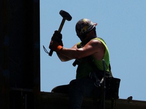 A construction worker installs steel beams on a high-rise building.