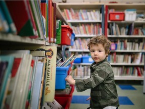 Dean Johnston, who is two years and 11 months old, looks through book shelves at the Montreal West Children's Library in Montreal on March 24, 2016. The Literacy Foundation says Gift of Reading campaign has distributed 860,000 books, helping to prevent reading and writing difficulties that can lead to illiteracy or students dropping out of school.