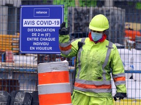 A security guard directs a tractor to a job site in Nuns' Island, in Montreal on May 11, 2020.