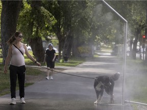 Jaclyn Lindover waits patiently while her dog Ovy enjoys a moment to stop for brief cool down in a city misting station on Mont-Royal Ave. last month.