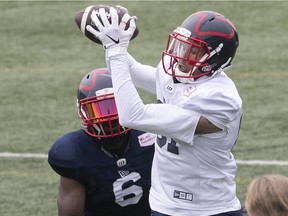 Montreal Alouettes wide-receiver Rashaun Simonise holds on to pass as he jumps in front of defensive-back Adarius Pickett during training-camp practice on July 20, 2021.