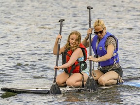 Jodi King shares a paddle board with her grand-daughter Olivia McDermott in the basin at Parc des Rapides in the LaSalle borough of Montreal on July 28, 2021.
