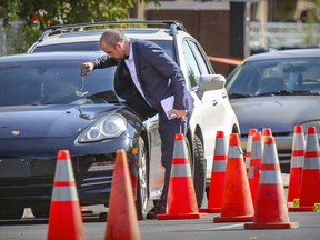 A Montreal police investigator examines a bullet hole in a car at the scene of a shooting in Rivière-des-Prairies  on Aug. 2, 2021 that left three people dead and two others injured.