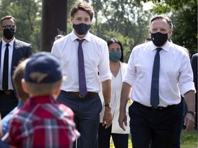 Liberal leader Justin Trudeau, left, and Quebec Premier François Legault stop to chat with 4-year-old Charles-Antoine Martel in Parc Lalancette in Montreal on Thursday, Aug. 5, 2021.
