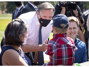 Quebec Premier François Legault stops to chat with 4 year old Charles-Antoine Martel as father Etienne Martel looks on in Parc Lalancette in Montreal on Thursday, August 5, 2021