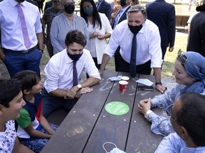 Prime Minister Justin Trudeau and Quebec Premier François Legault chat with a family at a park in the city's Hochelaga district on Thursday, Aug. 5, 2021.