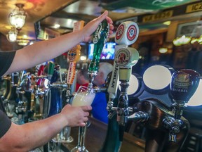 Manager Carlos Bustamante draws a pint of beer behind the bar at McKibbins Irish Pub in Montreal on Saturday, Aug. 8, 2020.