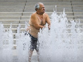 Marco Antonio Artiga cools off in the fountain at Place des Festivals in Montreal on Sunday, Aug. 8, 2021. Environment Canada issued a heat warning on Sunday for Montreal, Laval, the South Shore and surrounding regions.