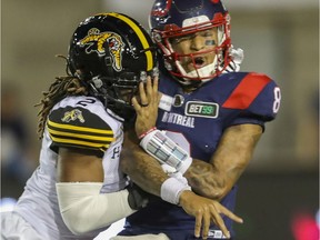 Alouettes quarterback Vernon Adams Jr. is hit by Tiger-Cats' Tunde Adeleke after throwing a pass during CFL action Friday night at Molson Stadium.