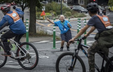 Volunteer Lyse Perreault guides bicyclists around the corner at rue Cherrier during the Tour de l'Île in Montreal on Aug. 29, 2021. Perreault has been volunteering for 30 years.