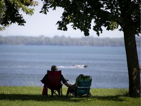 An elderly couple hold hands as they sit the shade and watch the boats go by as the city dealt with another hot day in Montreal, on Wednesday, Aug. 12, 2020. "If your parents lived a long time and your health is good, delaying QPP is an option worth a second look," Paul Delean writes.