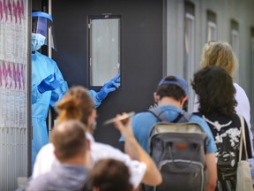 A health care worker invites people into the COVID-19 testing centre outside the Jewish General Hospital in Montreal Aug. 20, 2021.